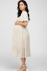 woman wearing a floral print maternity dress and holding her baby bump