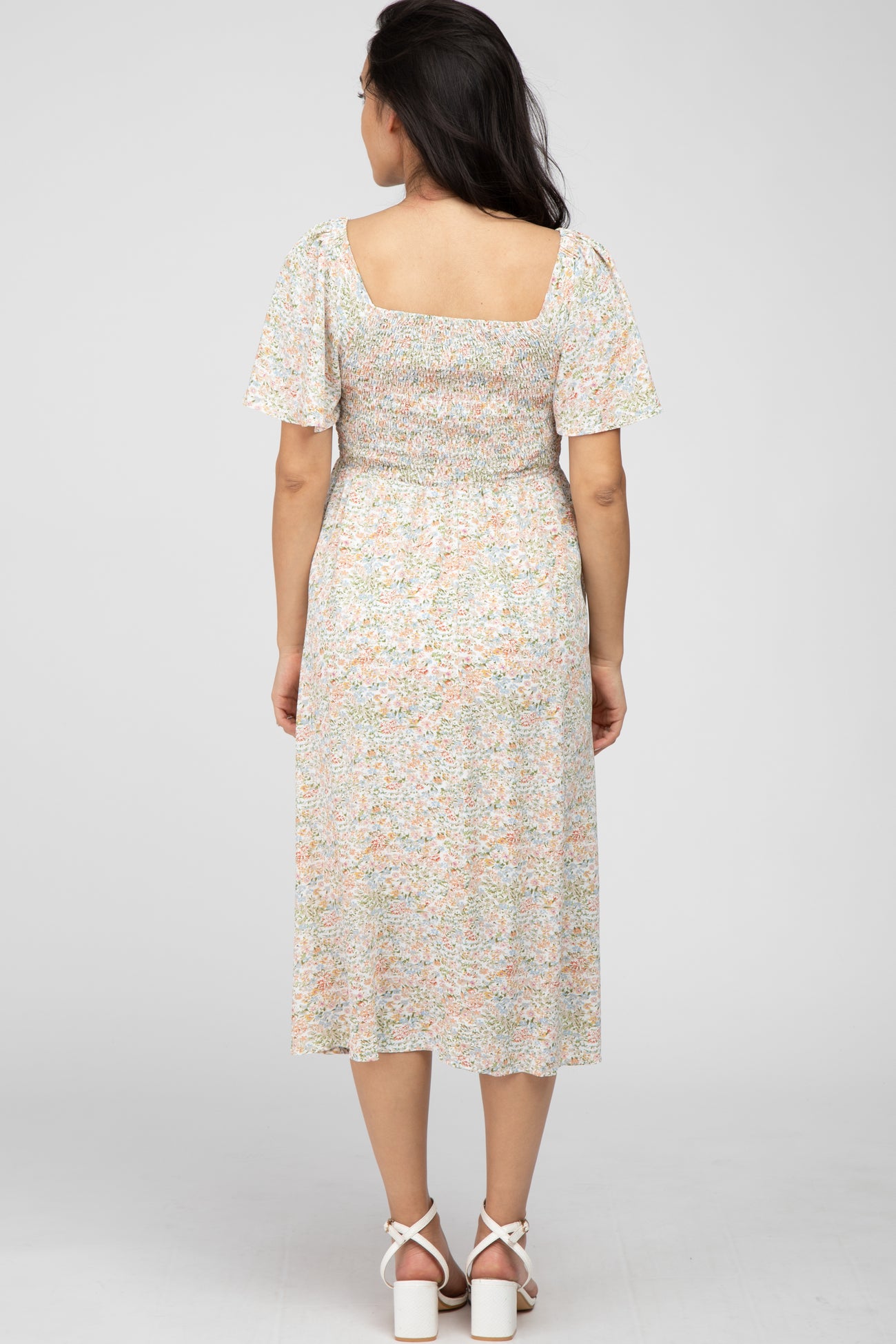 woman wearing a floral maternity dress with puff sleeves and a smocked bodice, view from the back