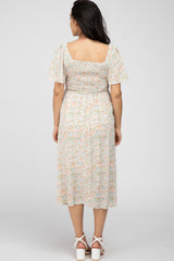 woman wearing a floral maternity dress with puff sleeves and a smocked bodice, view from the back