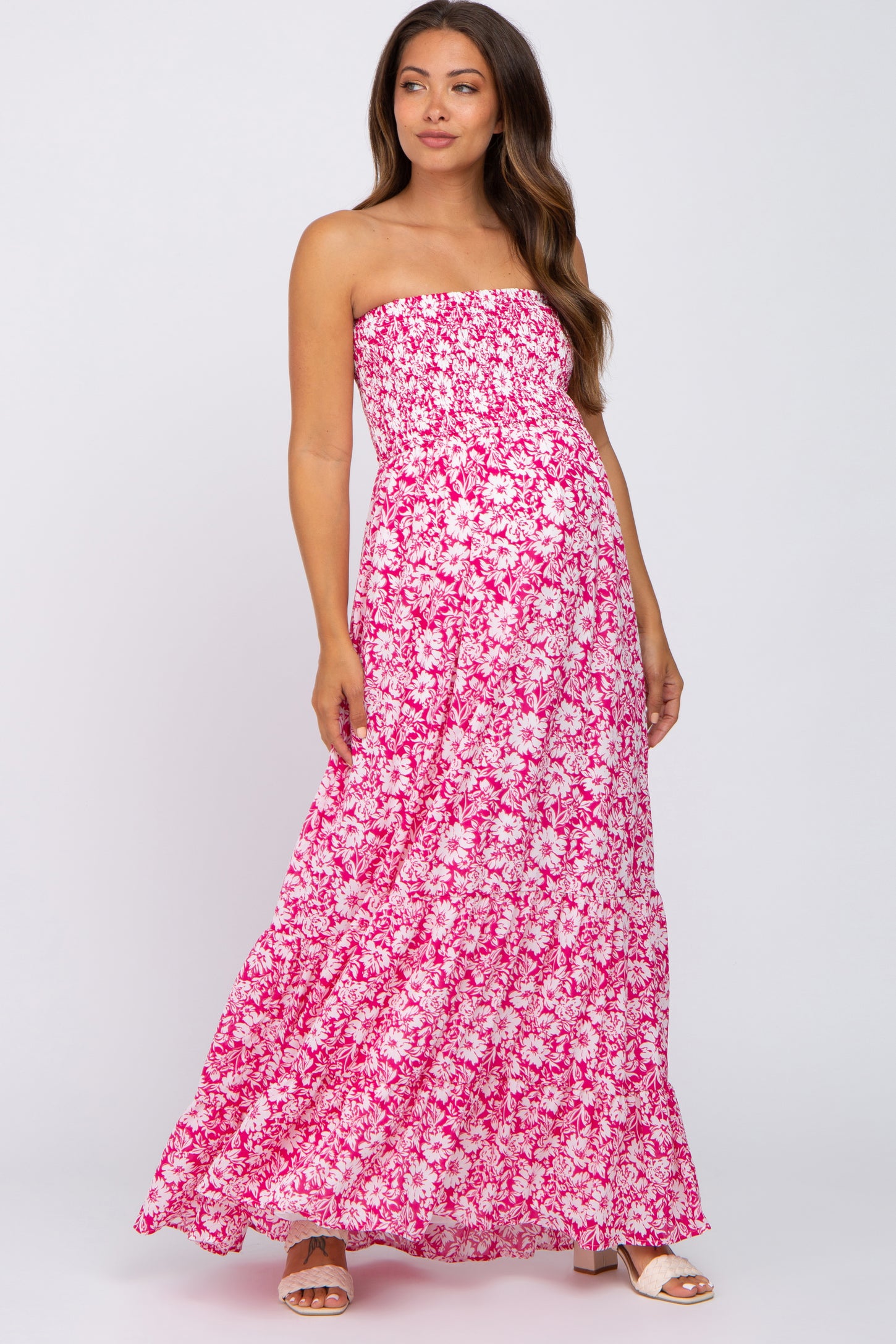 woman wearing a pink floral strapless maxi maternity dress with a fitted bodice and flowy skirt