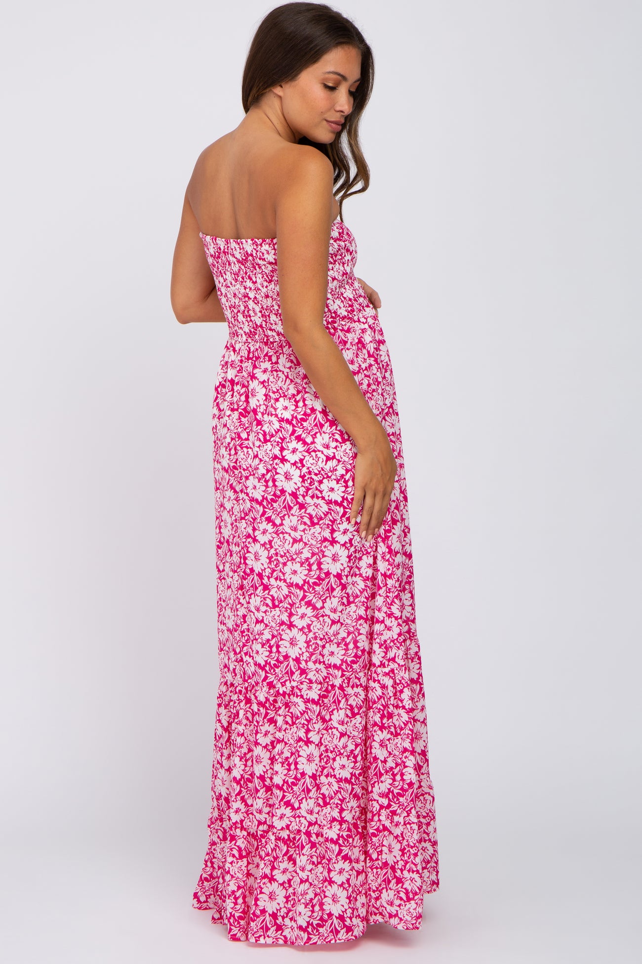 woman wearing a strapless pink floral maxi maternity dress showing her baby bump from the back