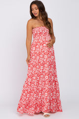 woman wearing a red floral strapless maternity maxi dress and holding her baby bump