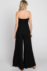 woman wearing a black strapless jumpsuit with a fitted bodice and wide-leg pants, viewed from the back