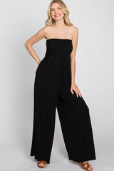 woman wearing a black strapless jumpsuit with a ruched bodice and wide-leg pants