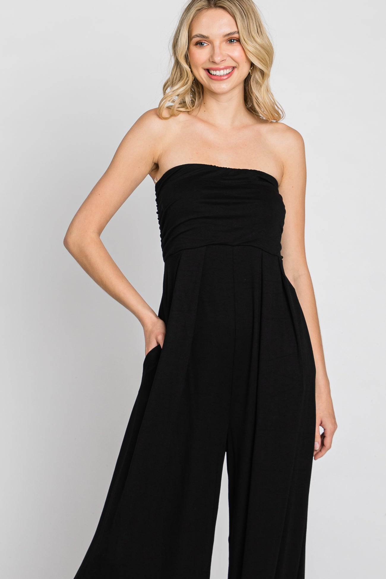 woman wearing a black strapless jumpsuit with a relaxed fit and side pockets