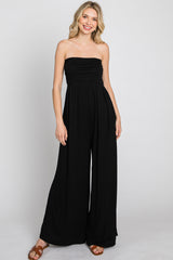 woman wearing a black strapless jumpsuit with a ruched bodice and wide-leg pants
