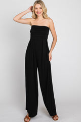 woman wearing a black strapless jumpsuit with a ruched bodice and wide-legged pants