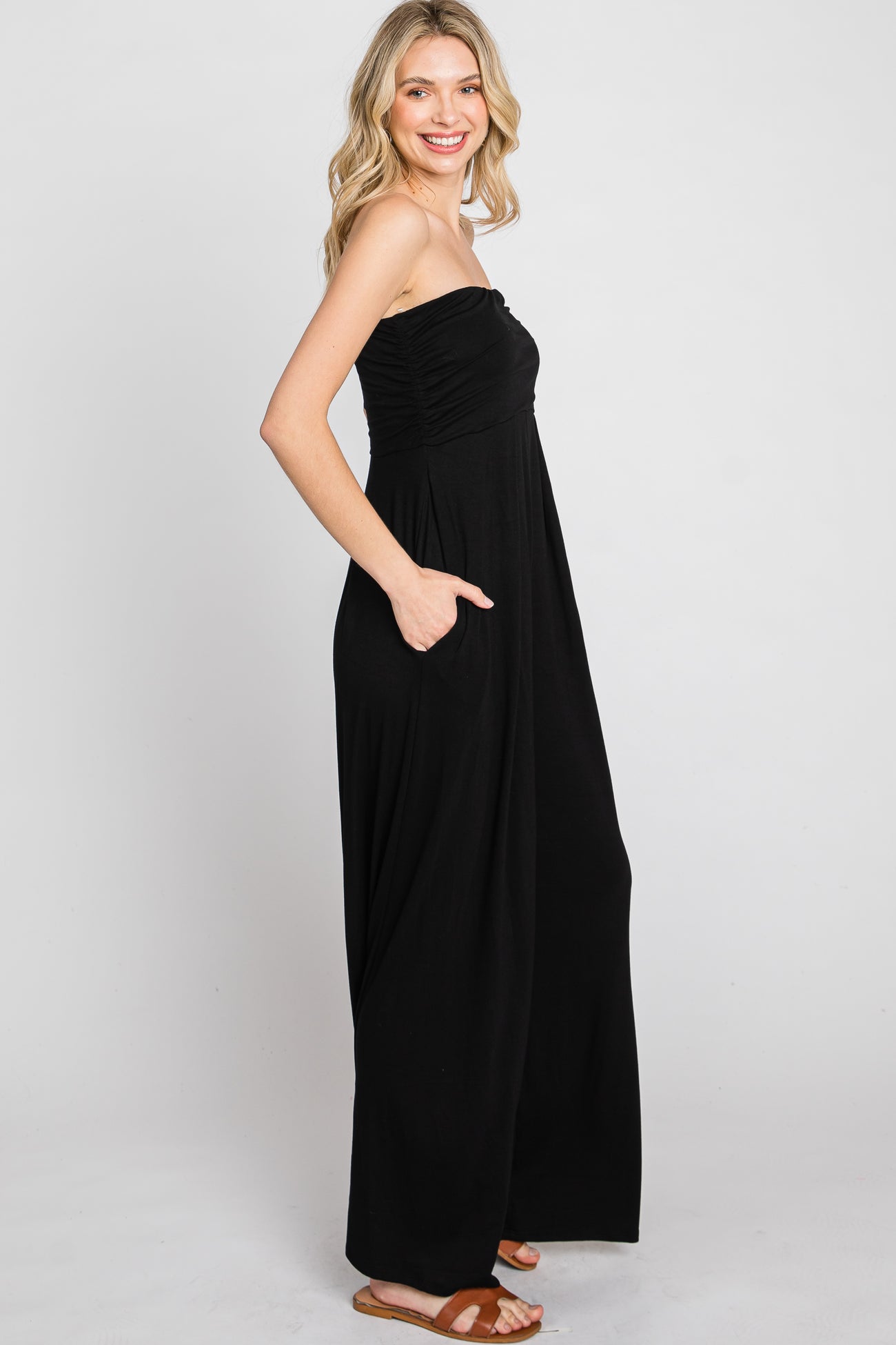 woman wearing a black strapless jumpsuit with side pockets and flowing legs