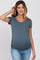 woman wearing a blue short sleeve maternity top, showcasing her baby bump, paired with light blue jeans