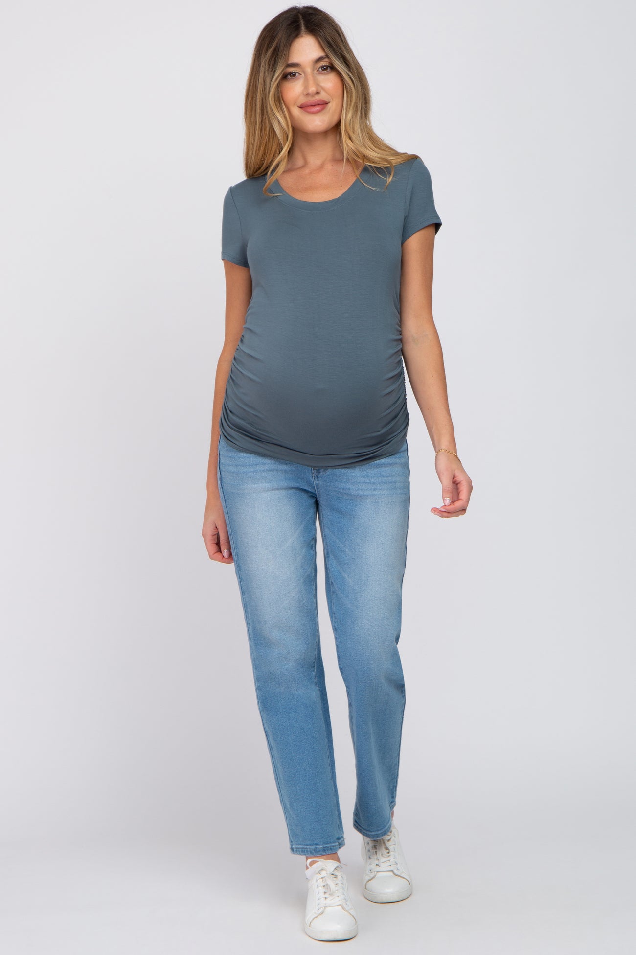 woman wearing a gray short sleeve maternity top and blue jeans, showing her baby bump
