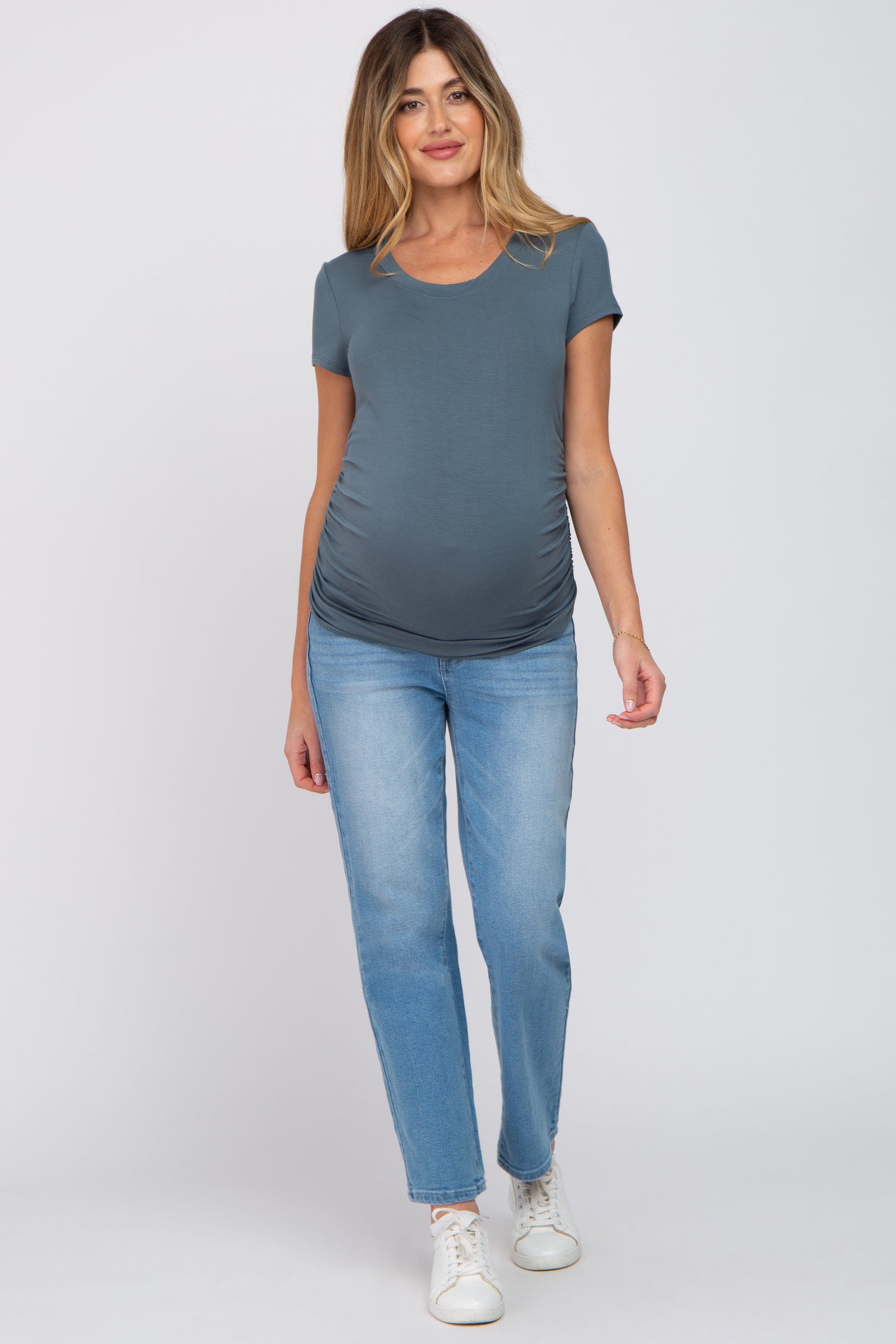 woman wearing a gray short sleeve maternity top and blue jeans, showing her baby bump