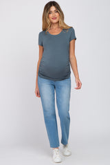 woman wearing a gray short sleeve maternity top and blue jeans, showing her baby bump