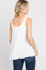 woman wearing a white sleeveless top with a bow detail on one shoulder and blue jeans, viewed from the back