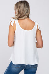 woman wearing a white maternity top with tie shoulder details and a relaxed fit, seen from the back