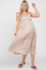 woman wearing a floral maternity midi dress with tie straps and a visible baby bump