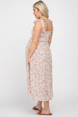woman wearing a floral print maternity dress with ruffled straps and a visible baby bump, seen from the side