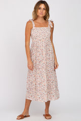 woman wearing a white floral midi dress with square neckline and tie straps, standing in sandals