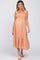 woman wearing a peach maternity dress with frill straps and a flowing skirt, showcasing her baby bump