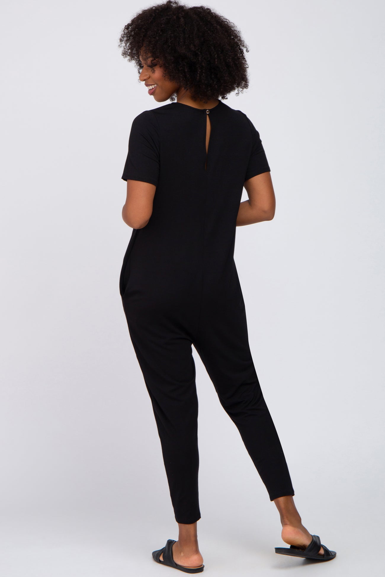 woman wearing a black short sleeve jumpsuit with a keyhole back detail and tapered pants