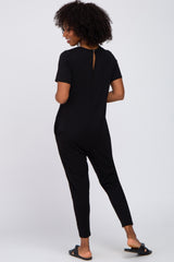 woman wearing a black short sleeve jumpsuit with a keyhole back detail and tapered pants