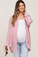 woman wearing a light pink maternity button-up shirt over a white tank top and blue jeans, showing a baby bump