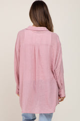 woman wearing a loose-fitting pink maternity top with a button detail and relaxed silhouette, viewed from the back