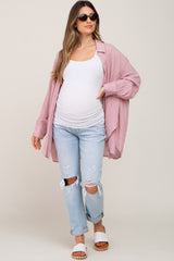woman wearing a pink oversized button-up shirt, white tank top, distressed light wash jeans, and sunglasses, with a baby bump visible