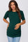 woman wearing a dark green short sleeve maternity top with puff sleeves and ruched detailing, holding her baby bump
