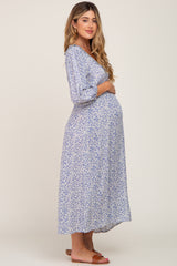 woman wearing a floral print maternity maxi dress and holding her baby bump