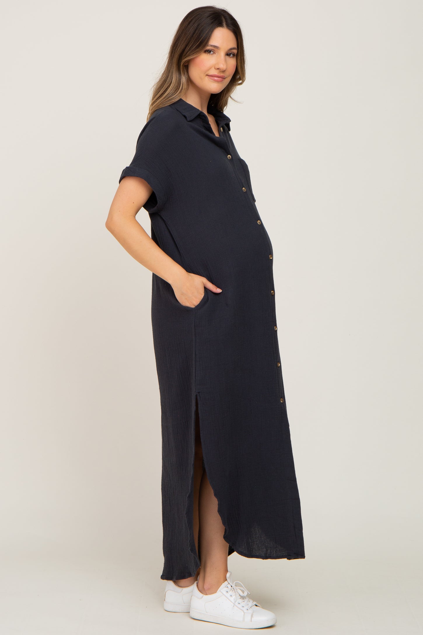 woman wearing a navy blue short sleeve maternity dress with buttons and pockets, featuring a visible baby bump
