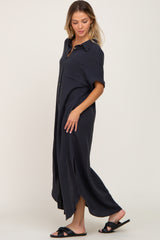 woman wearing a navy blue button-up maxi dress with short sleeves and side slits, standing in profile