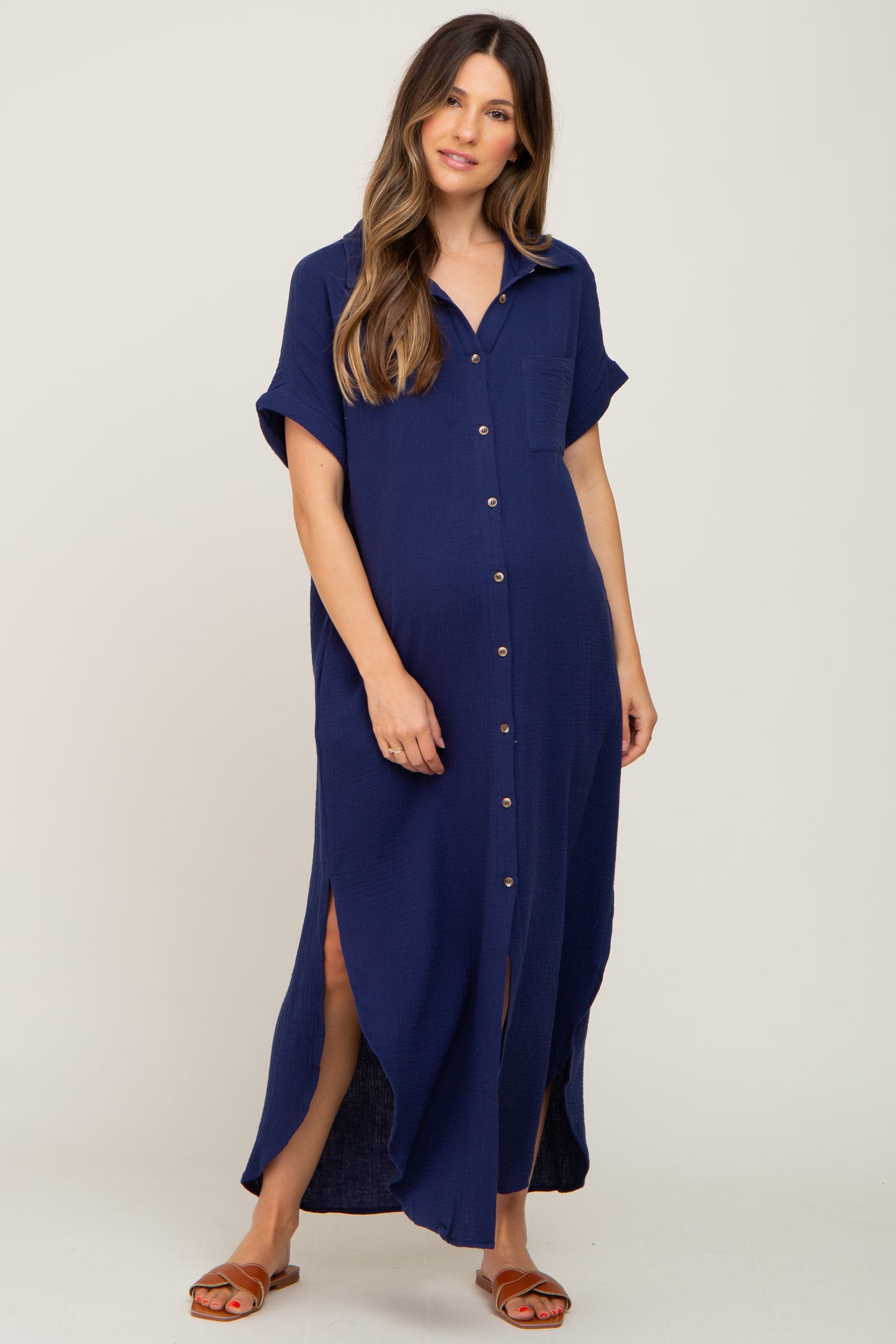 woman wearing a navy blue short sleeve button-up maternity dress with side slits and a front pocket