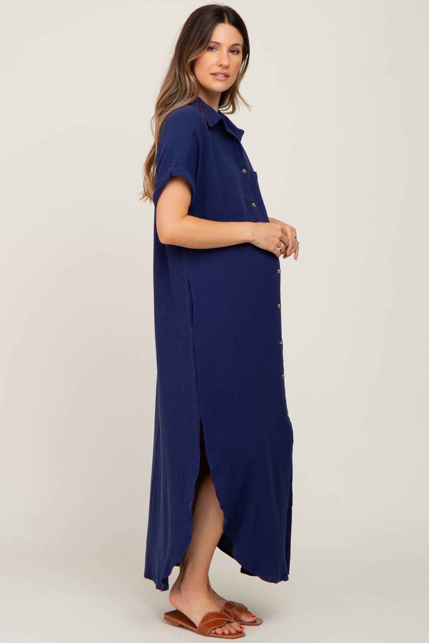 woman wearing a navy blue button-up maternity dress with short sleeves and side slits, showing her baby bump