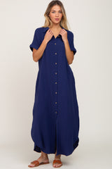woman wearing a navy blue short sleeve button-up maxi dress with a front pocket and side slits