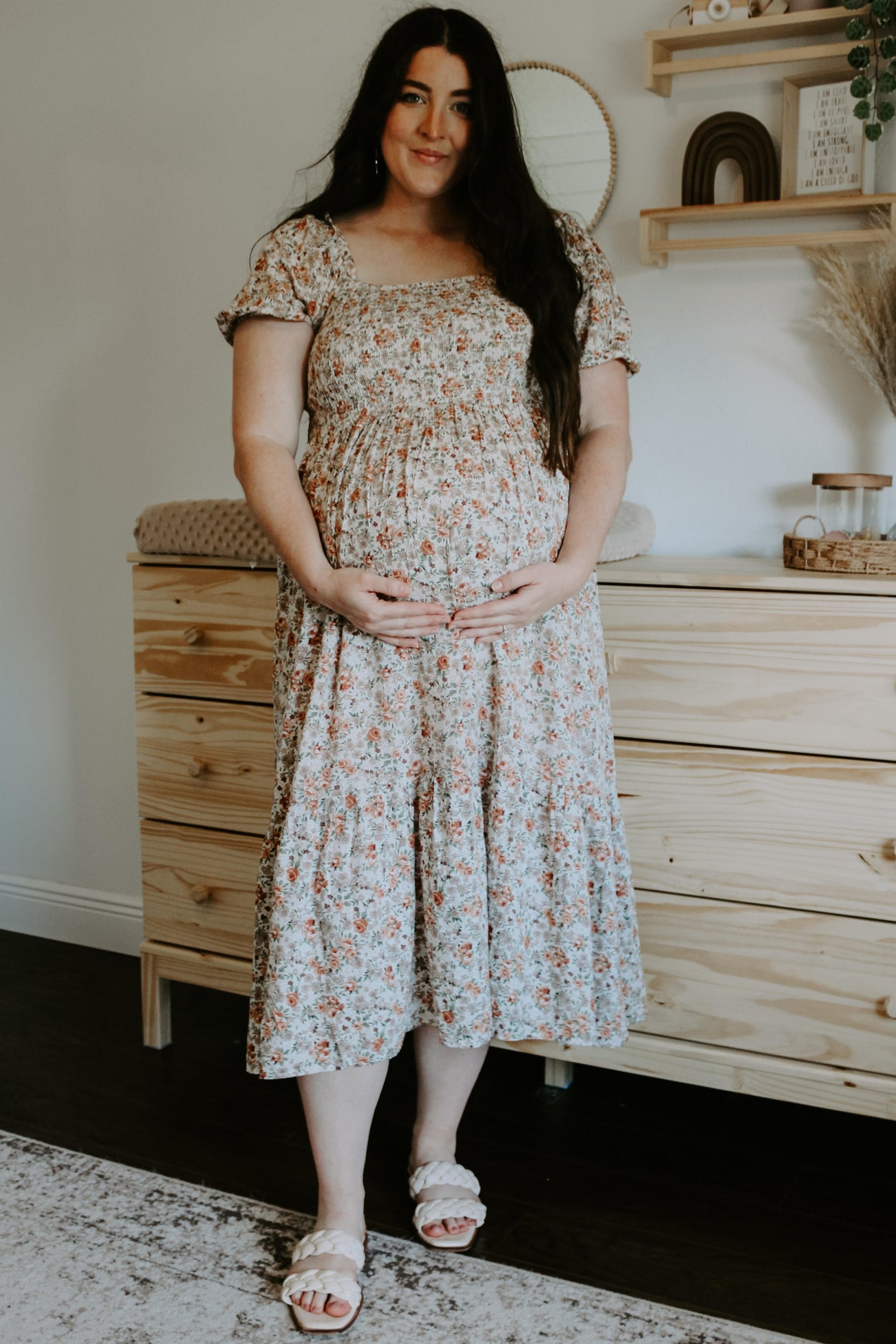 woman wearing a floral maternity dress and holding her baby bump