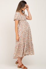 woman wearing a floral print maternity dress with short puff sleeves and a flowing skirt, gently touching her baby bump
