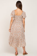 woman wearing a floral print maternity dress with puff sleeves and a tiered hemline, showing a baby bump from the back