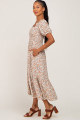 woman wearing a floral midi dress with puff sleeves and pockets, styled with brown heeled sandals