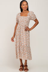 woman wearing a floral midi dress with puff sleeves and a square neckline, posing with one hand on her hip