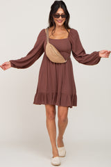 woman wearing a brown long sleeve mini dress with a ruffled hem and a tan fanny pack, styled with sunglasses