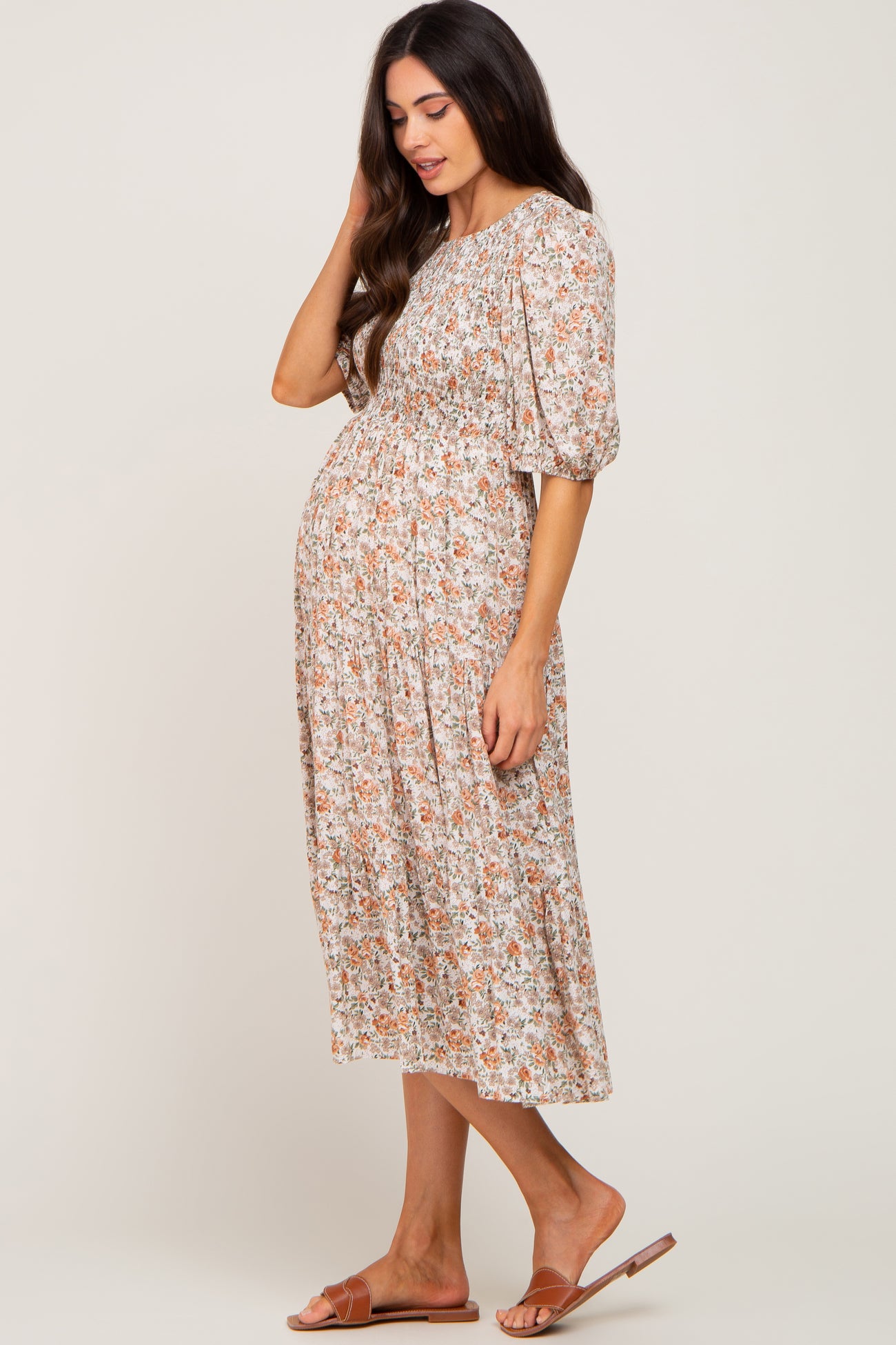 woman wearing a floral maternity dress with puff sleeves and a smocked bodice, showing her baby bump