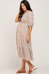 woman wearing a floral maternity dress with puff sleeves and a smocked bodice, showing her baby bump