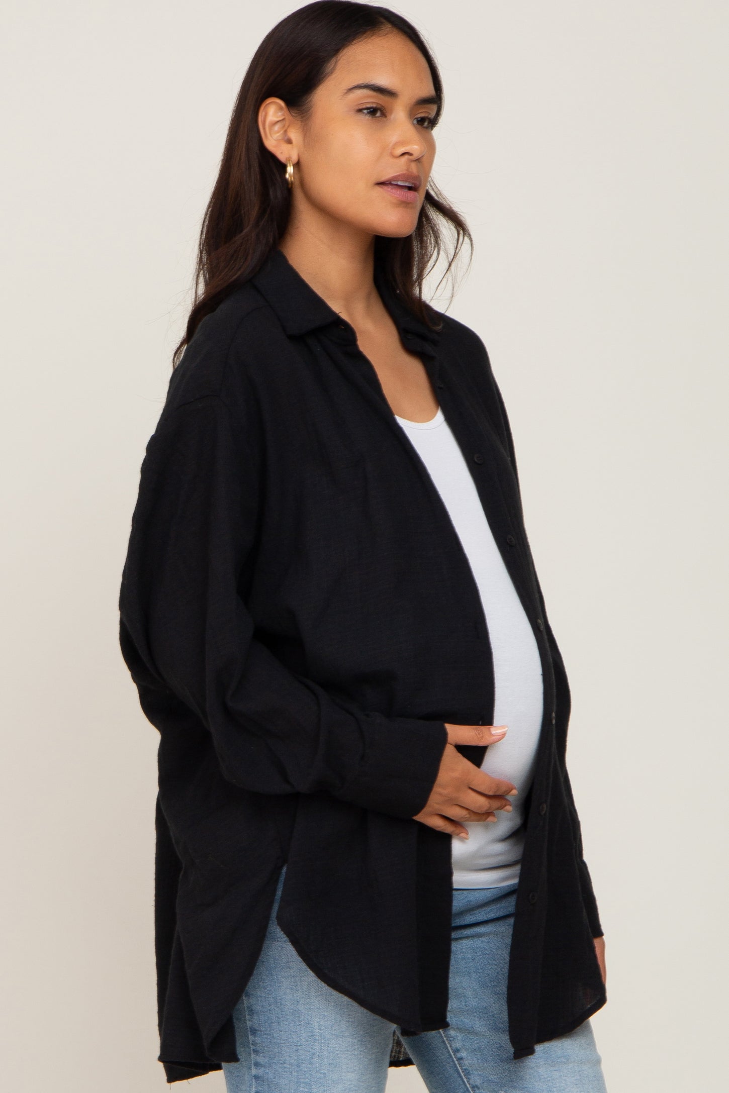 woman wearing a black button-up maternity shirt and holding her baby bump
