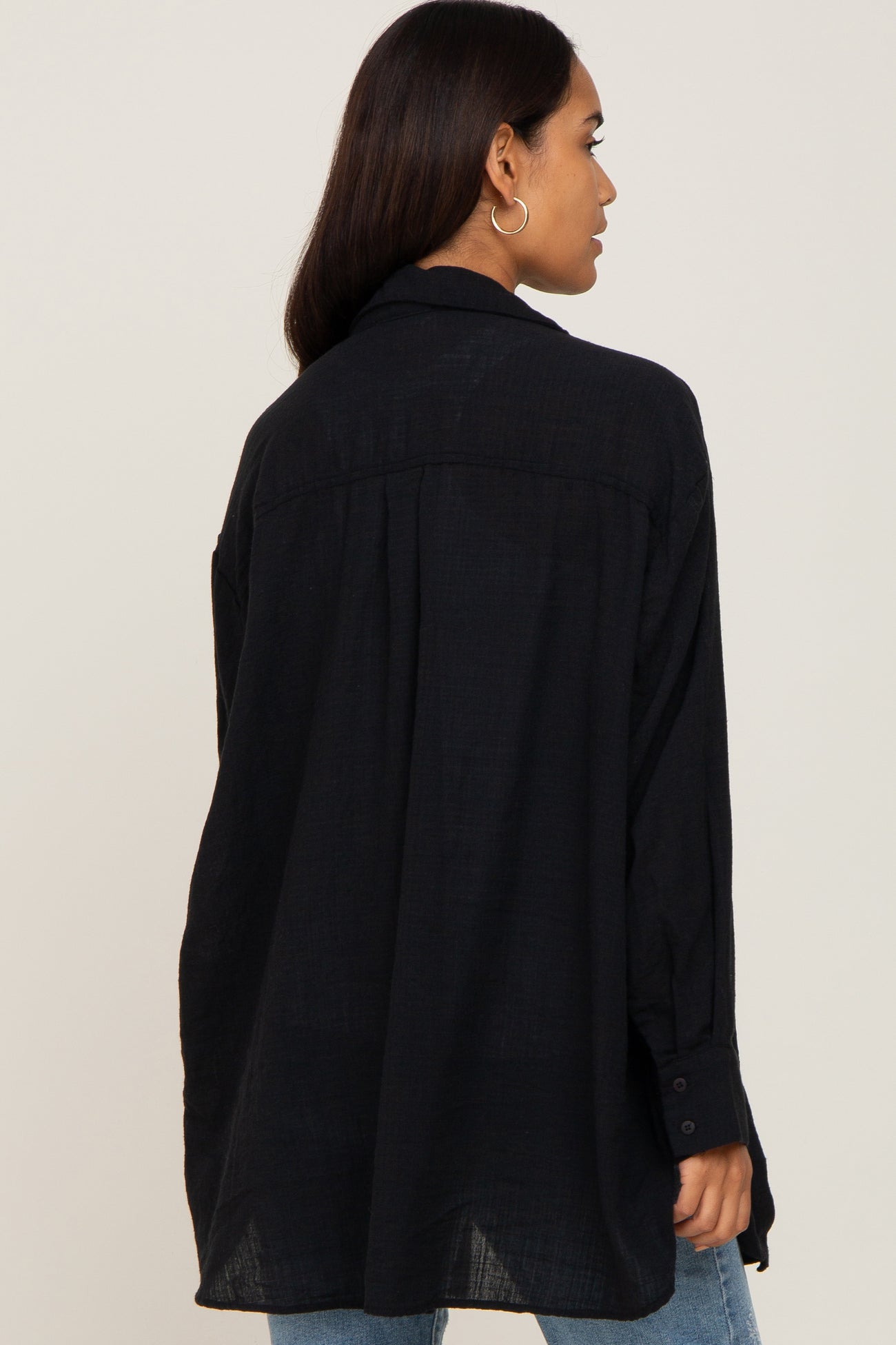 woman wearing a dark navy oversized maternity shirt with a relaxed fit and button details on the sleeves