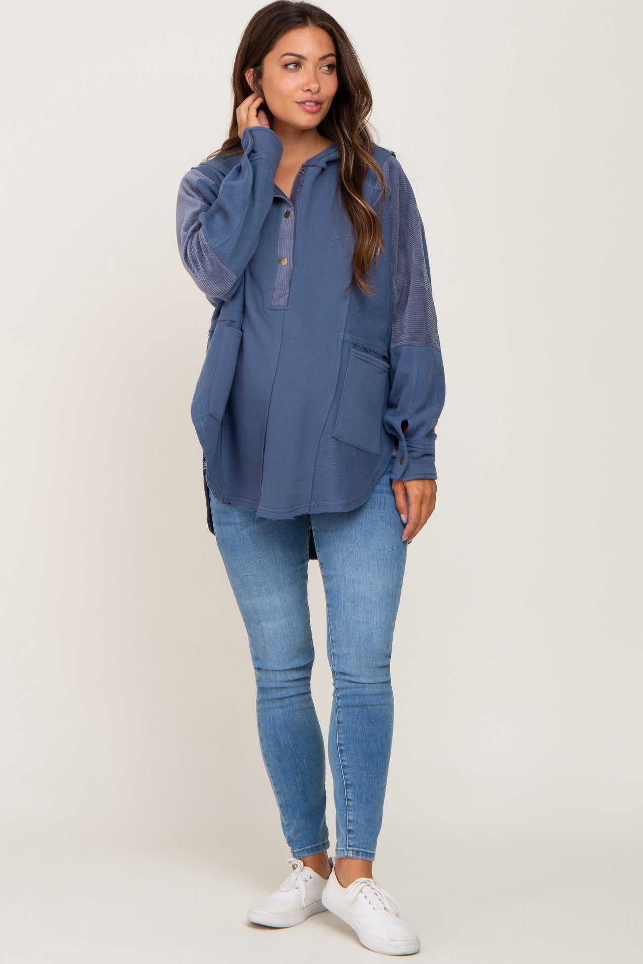woman wearing a navy blue maternity pullover with a button-down collar and pockets, paired with skinny jeans