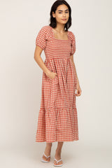 woman wearing a red and white gingham puff sleeve maxi dress with a square neckline and pockets