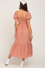 woman wearing a red and white gingham maternity dress with puffy sleeves and a tiered hemline