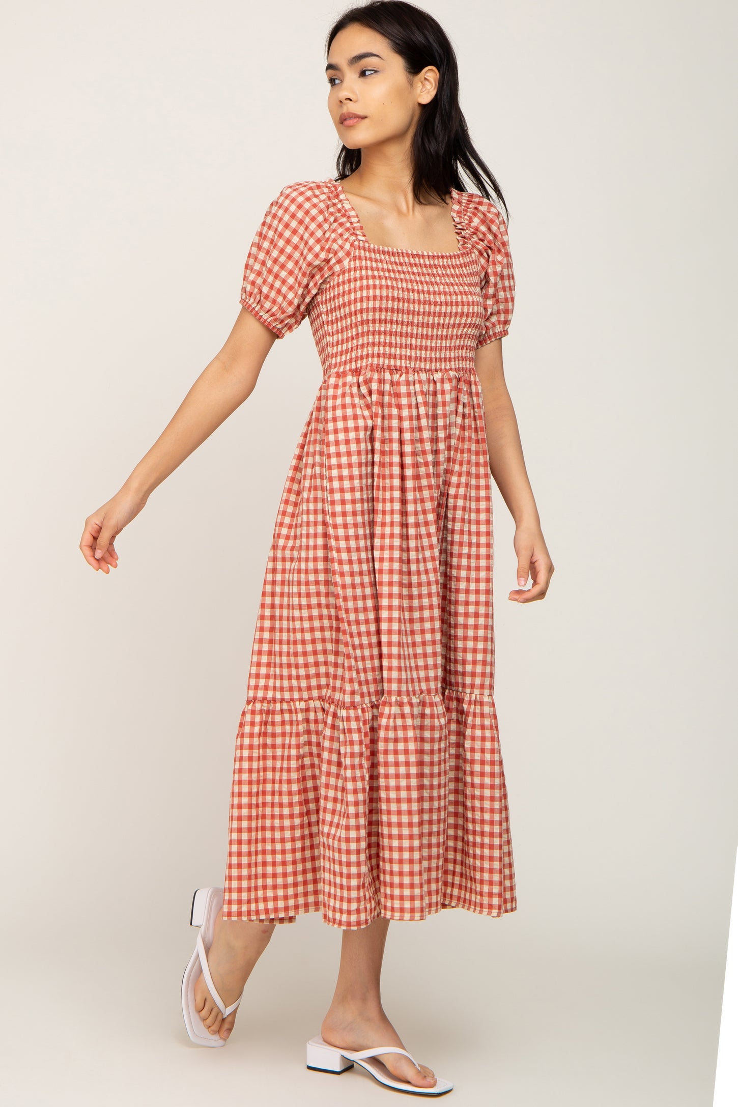 woman wearing a red and white gingham midi dress with puff sleeves and a tiered skirt