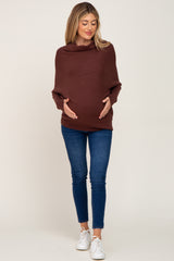 pregnant woman wearing a brown cowl neck maternity sweater and blue skinny jeans with white sneakers