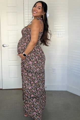 woman wearing a floral print maternity maxi dress and proudly showcasing her baby bump
